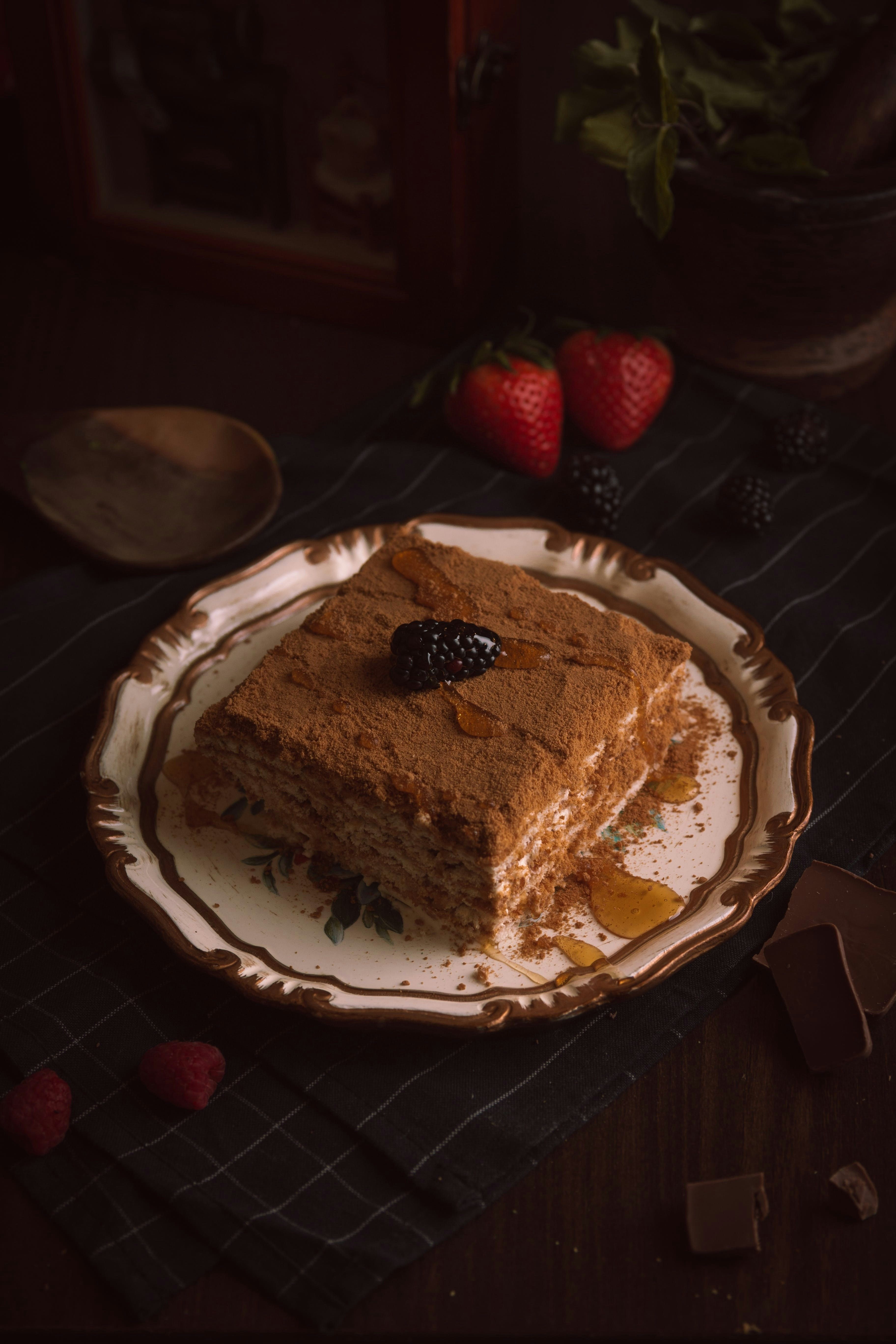 Tiramisu served on a plate with blueberry and honey on top of the tiramisu